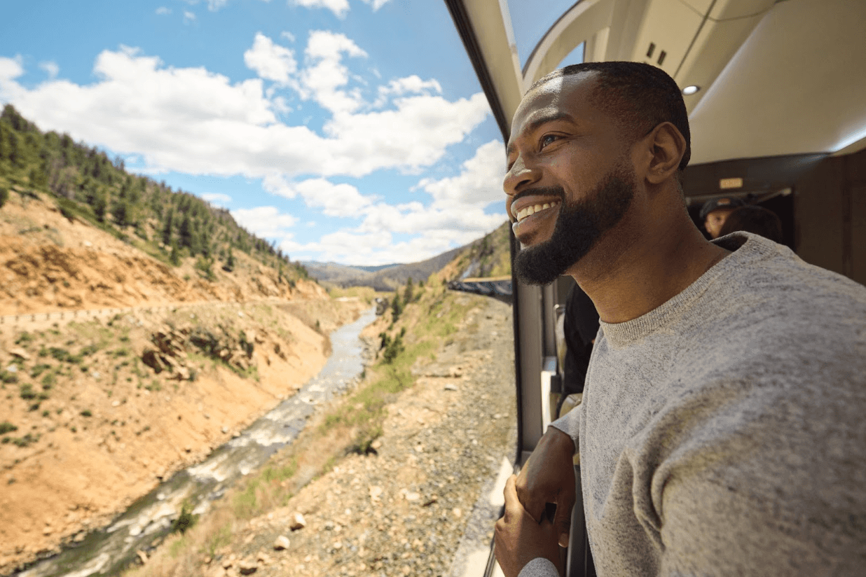 A man gazes out the window of the Rocky Mountaineer train as it runs alongside the Colorado River
