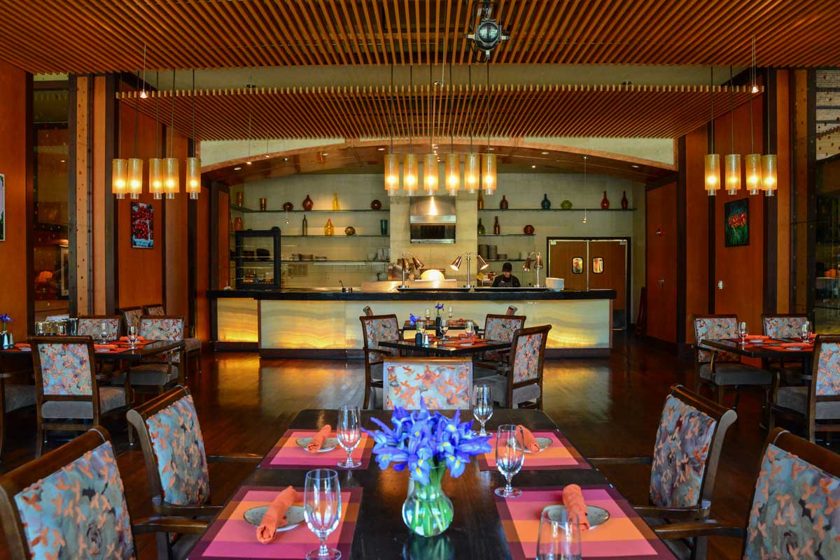 An empty dining area at Jill’s Restaurant at St. Julian Hotel and Spa, with hanging lights and bright-pink placemats.