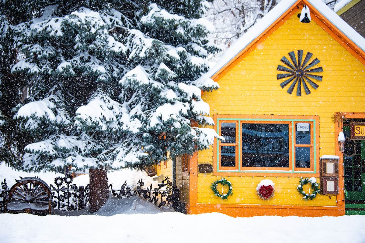 Snow falling around a yellow bungalow building that houses a restaurant