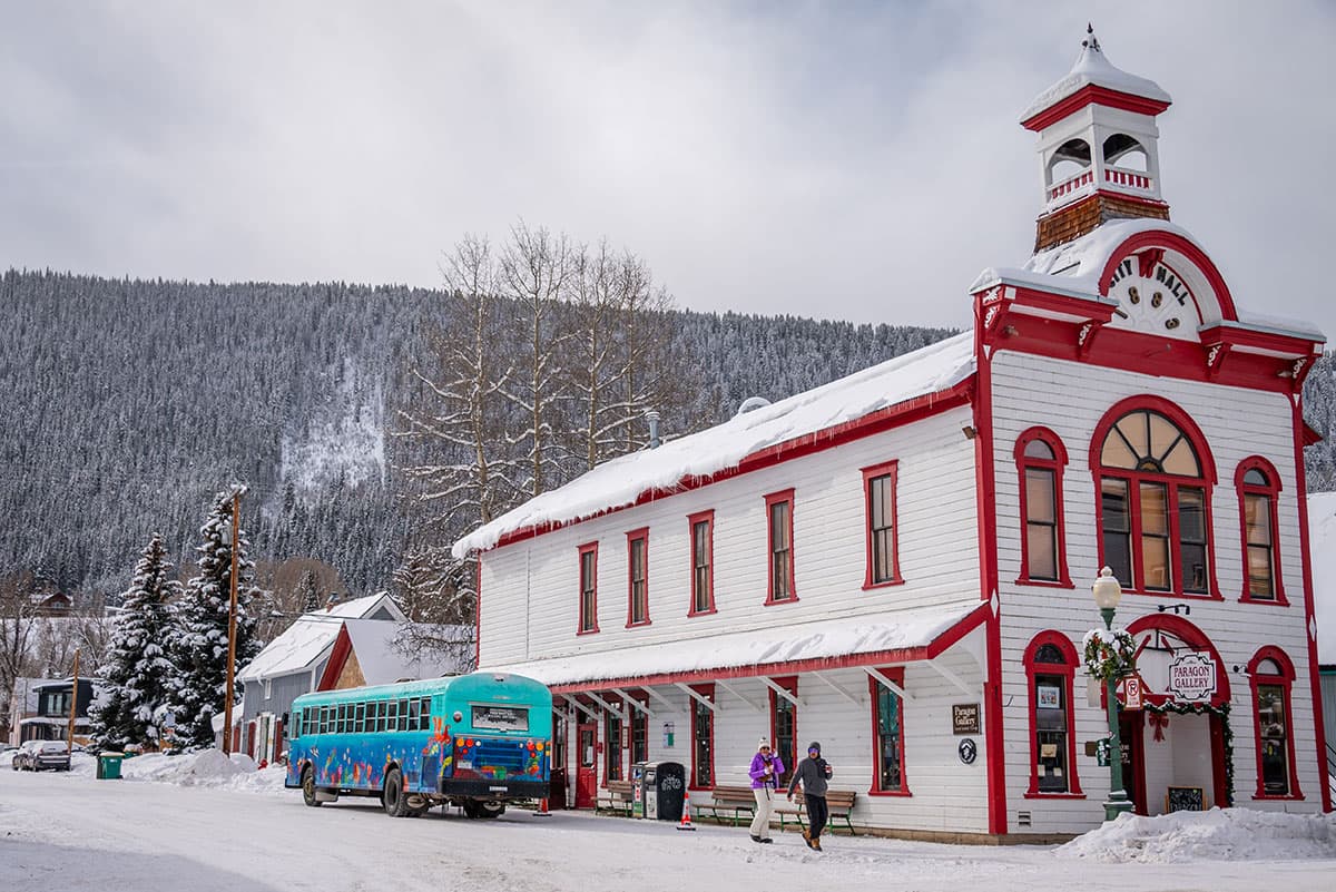 White Victorian-style city hall building with red trim on a snowy, small-town street
