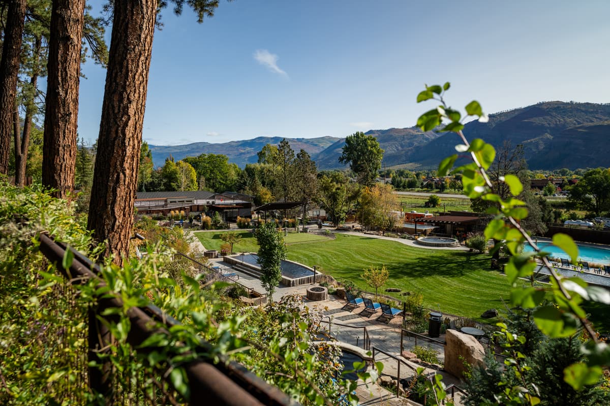 View of the many soaking pools of Durango Hot Springs in Colorado in lush, green summer with the mountains in the background