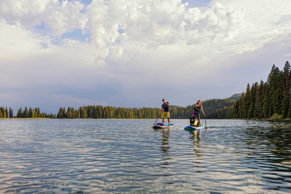Two people stand-up paddleboarding on one of Grand Mesa's many calm lakes