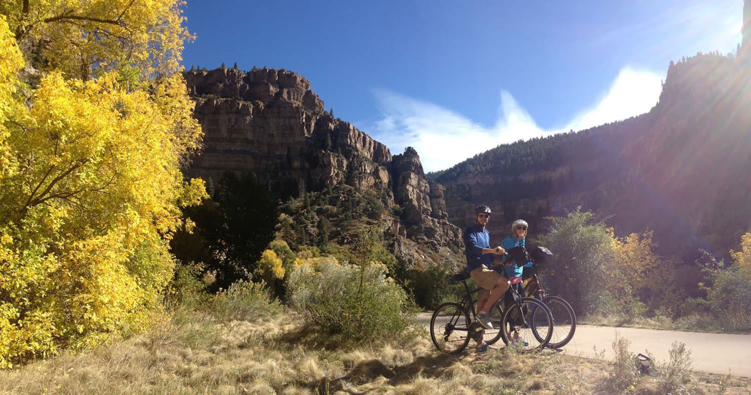 Two people in athletic gear stand next to their bikes on a trail in Glenwood Springs
