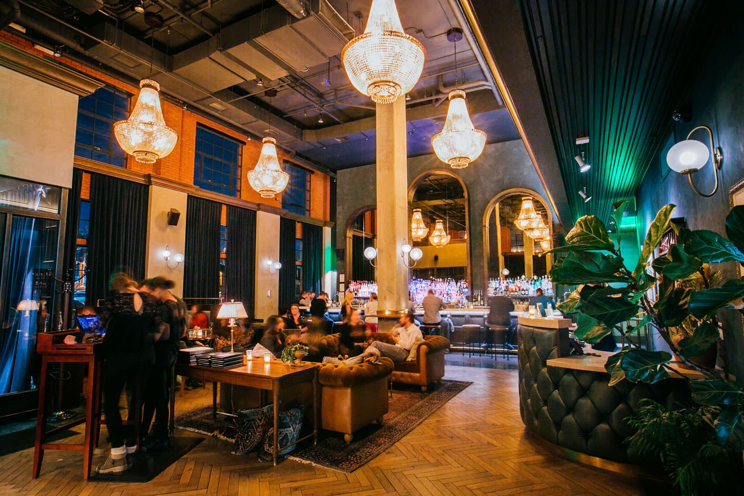 Elegant, multi-tiered chandeliers are set aglow and slight up the chic and modern lounge spaces at Death & Co in the Ramble Hotel in Denver, Colorado.