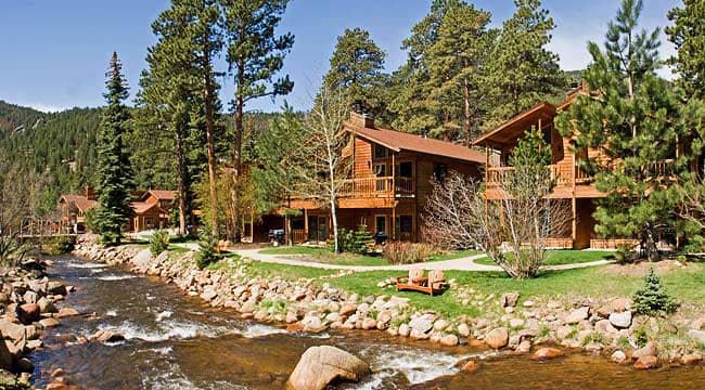A river runs past the Fall River cabins in Estes Park, CO on a blue-sky day