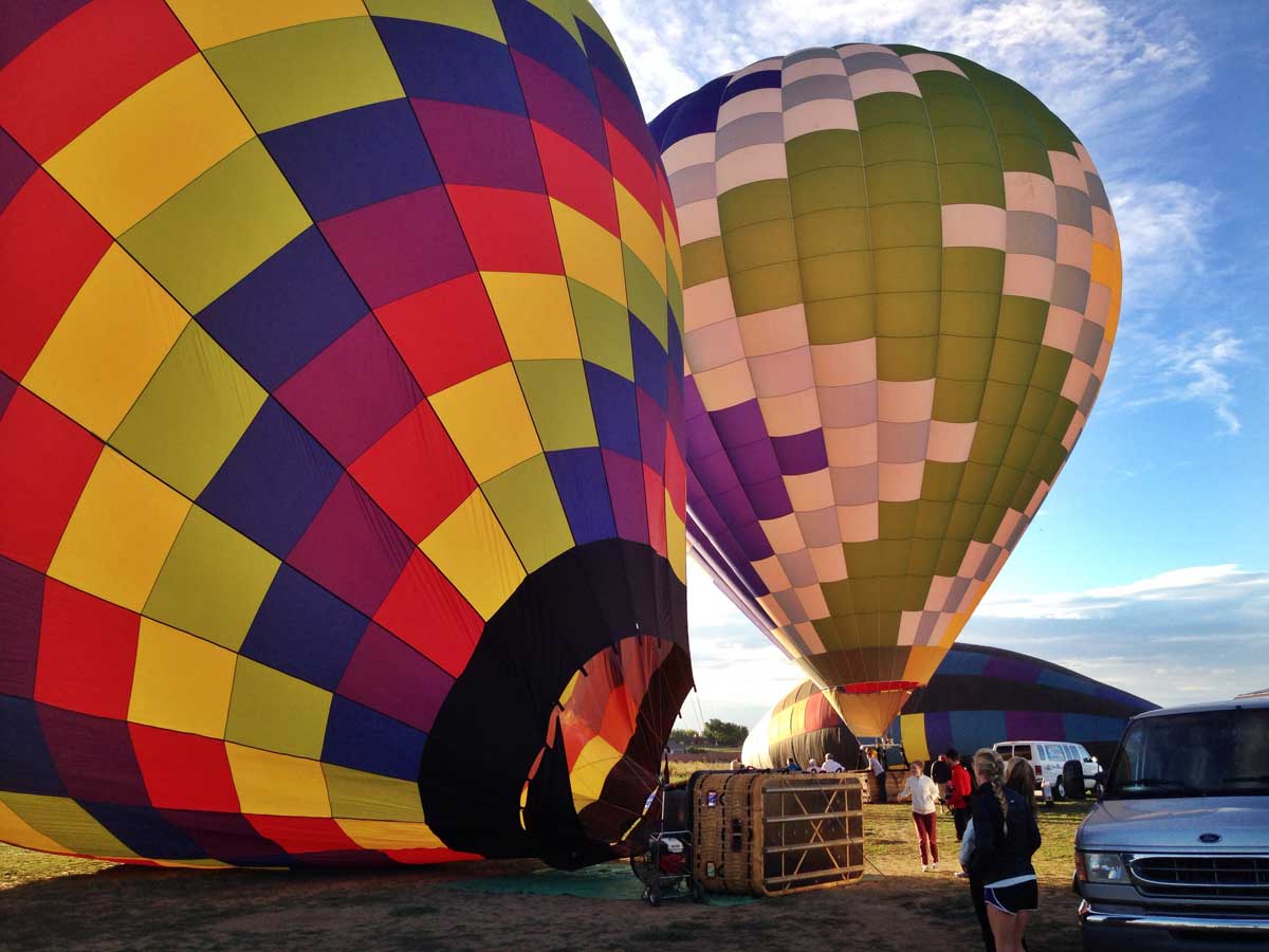 Two colorful hot-air balloons before liftoff with a mountain silhouette in the background