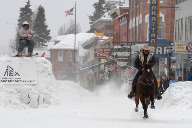 A man on horseback rides down a snowy downtown street