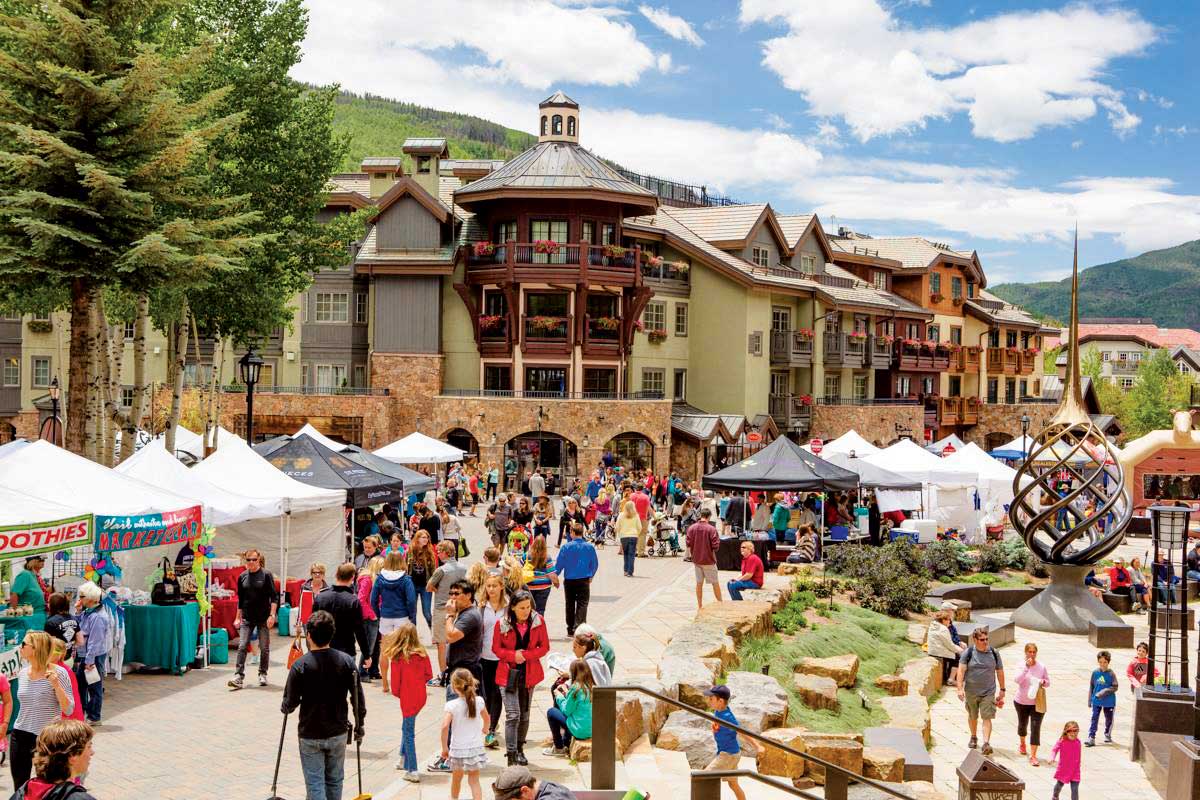 Vail Village visitors view the fares of local farmers and vendors at tented booth around the pedestrian-only walkways in Vail, Colorado.