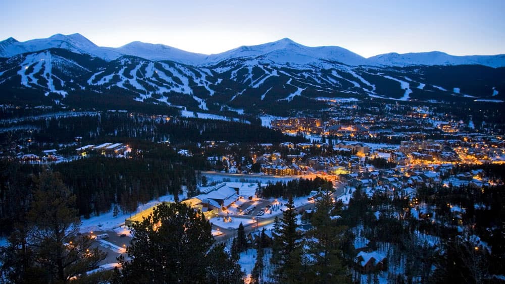 Dusk sets in on the ski slopes of Breckenridge and the town's lights glow from the valley floor