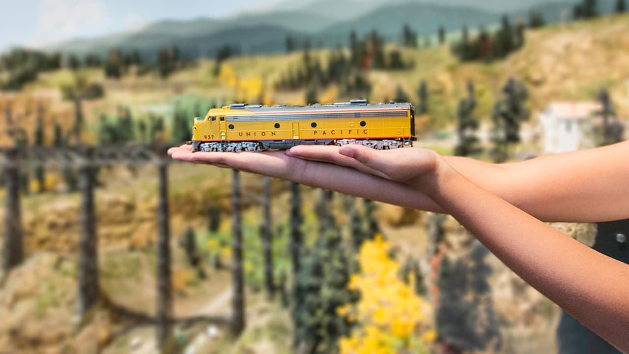 Outside the Colorado Model Railroad Museum in Greeley, a child lays a small, aspen-gold model of the Union Pacific train across their hands and an arm.