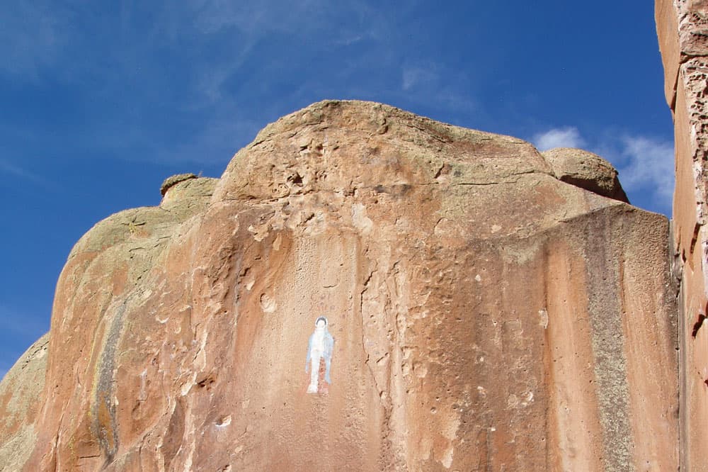 A partially worn away painted figure can be seen towards the top of a red rockface in Penitente Canyon in Colorado.