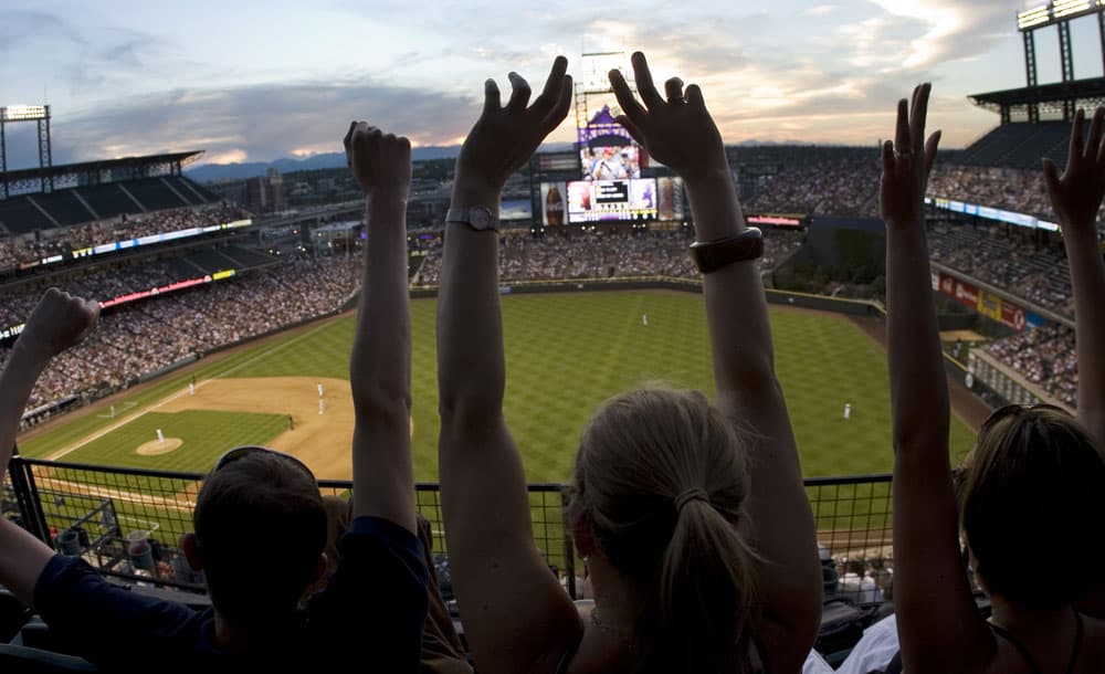 Fans raise their arms to cheer on the Rockies from the top level of Coors Field in Denver, Colorado.