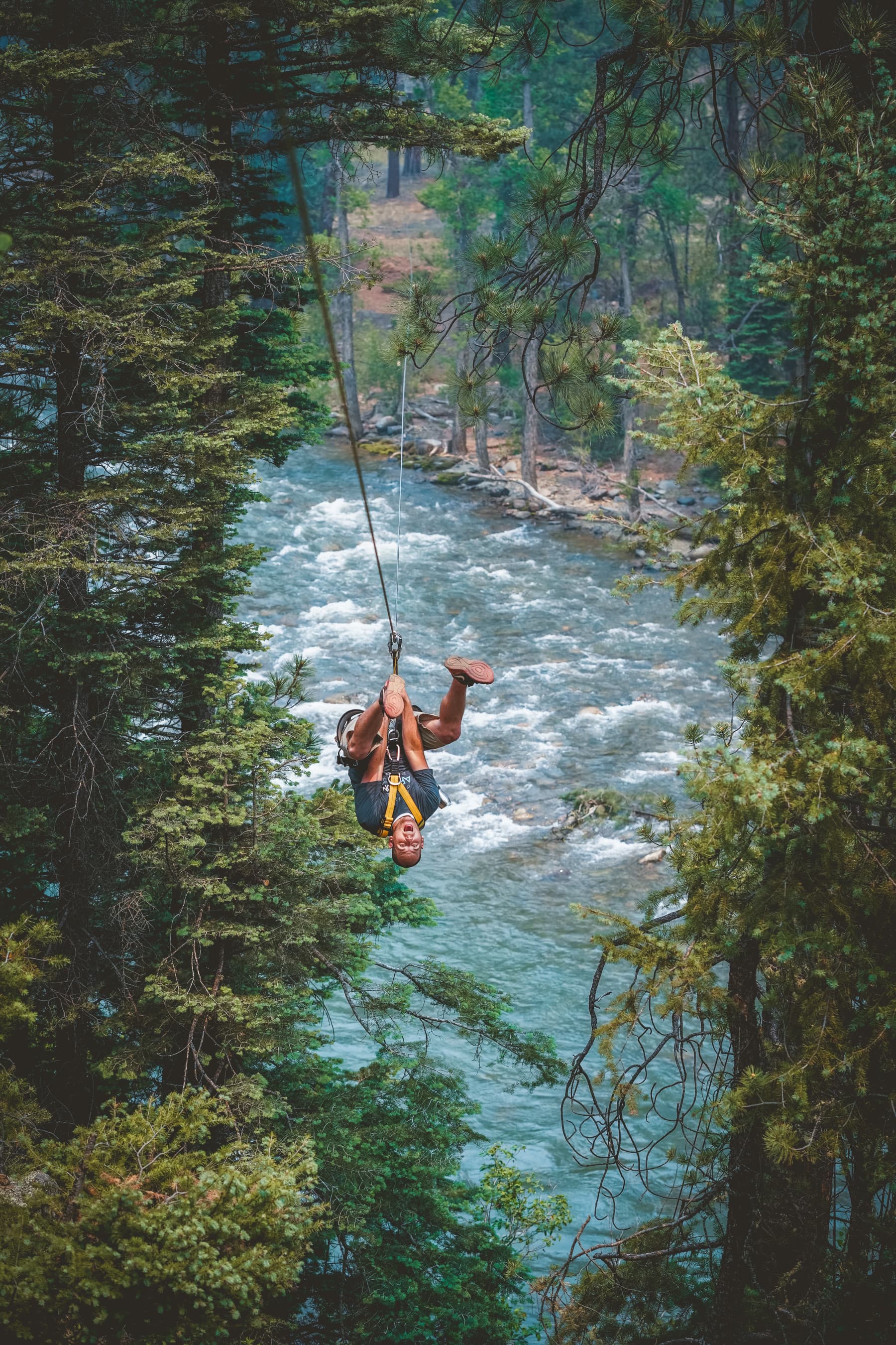 guest trying out some tricks during a long zip line over the river photo 7