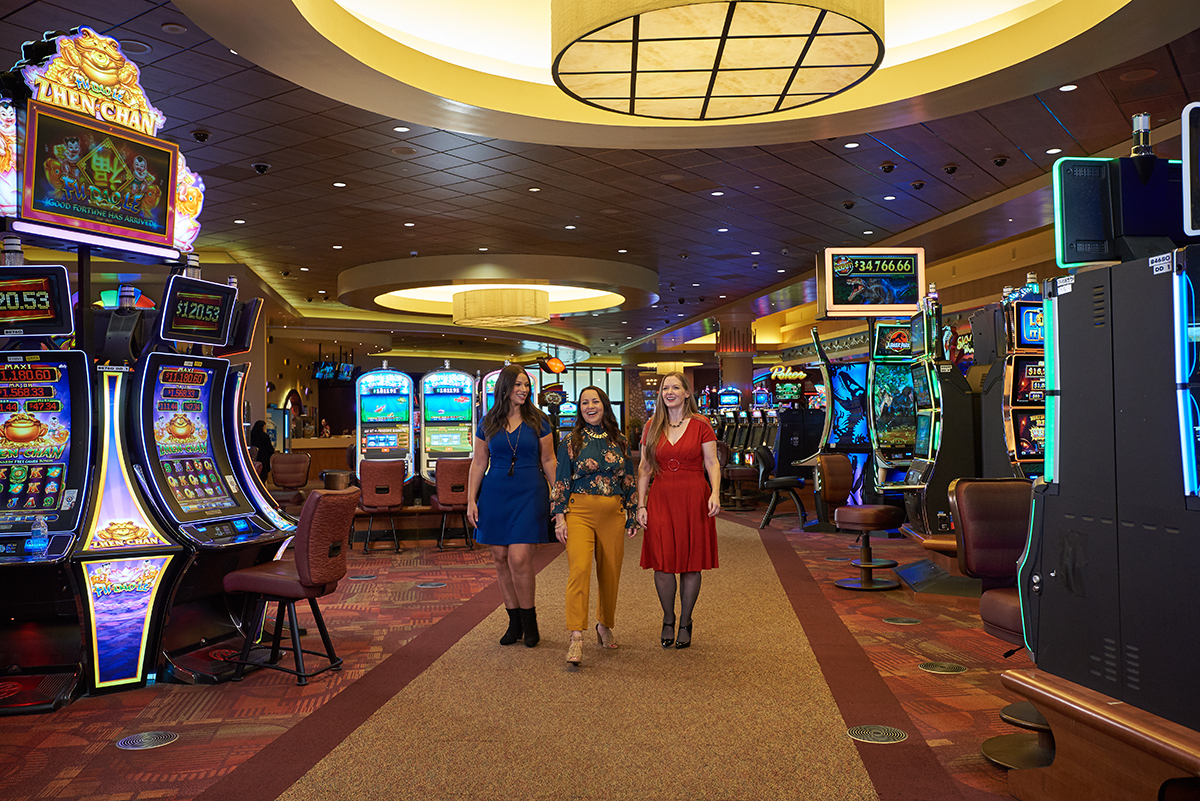 Two women on the walkway between the slot machines inside a modern casino