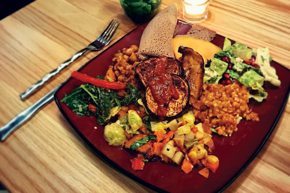 A plate of Ethiopian cuisine, including root veggies, rice, various meats and injera (flatbread)