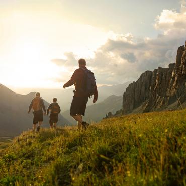 Facebook Three adults hiking along a grassy trail.