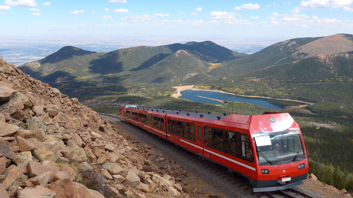 Pikes Peak train with alpine lake and mountains in the background