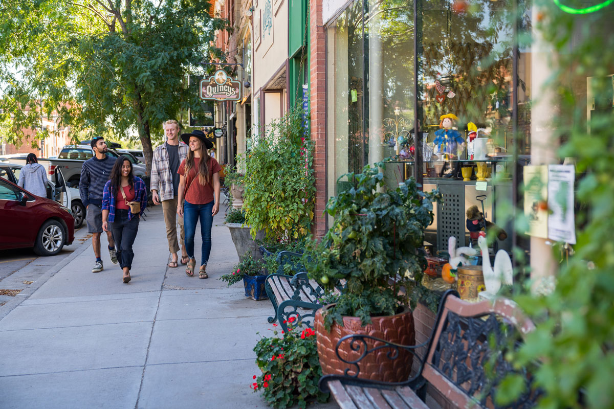 A group of happy friends walks the sidewalks of downtown Cañon City on a sunny day.