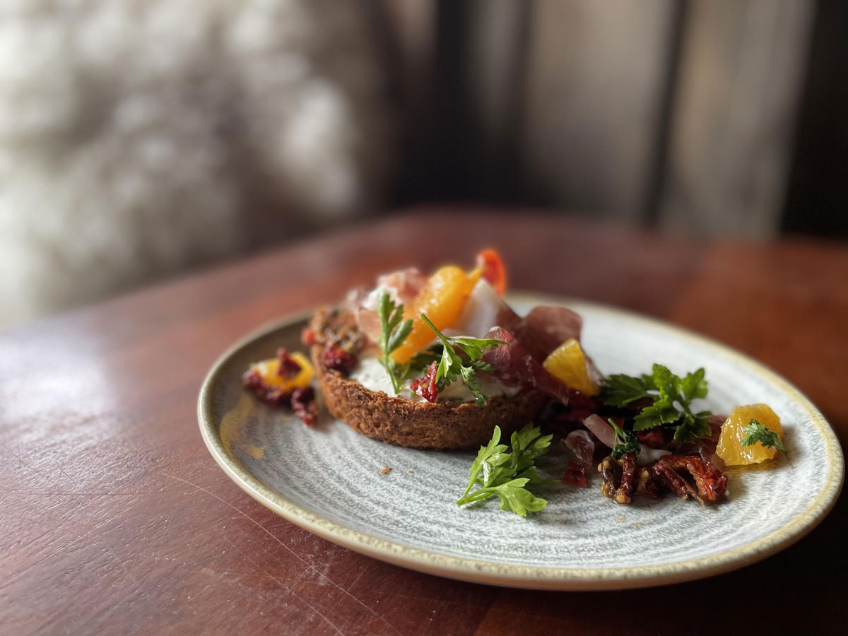 A savory tart topped with ham, citrus, fresh mint and candied nuts at Bramble and Hare in Boulder, Colorado.