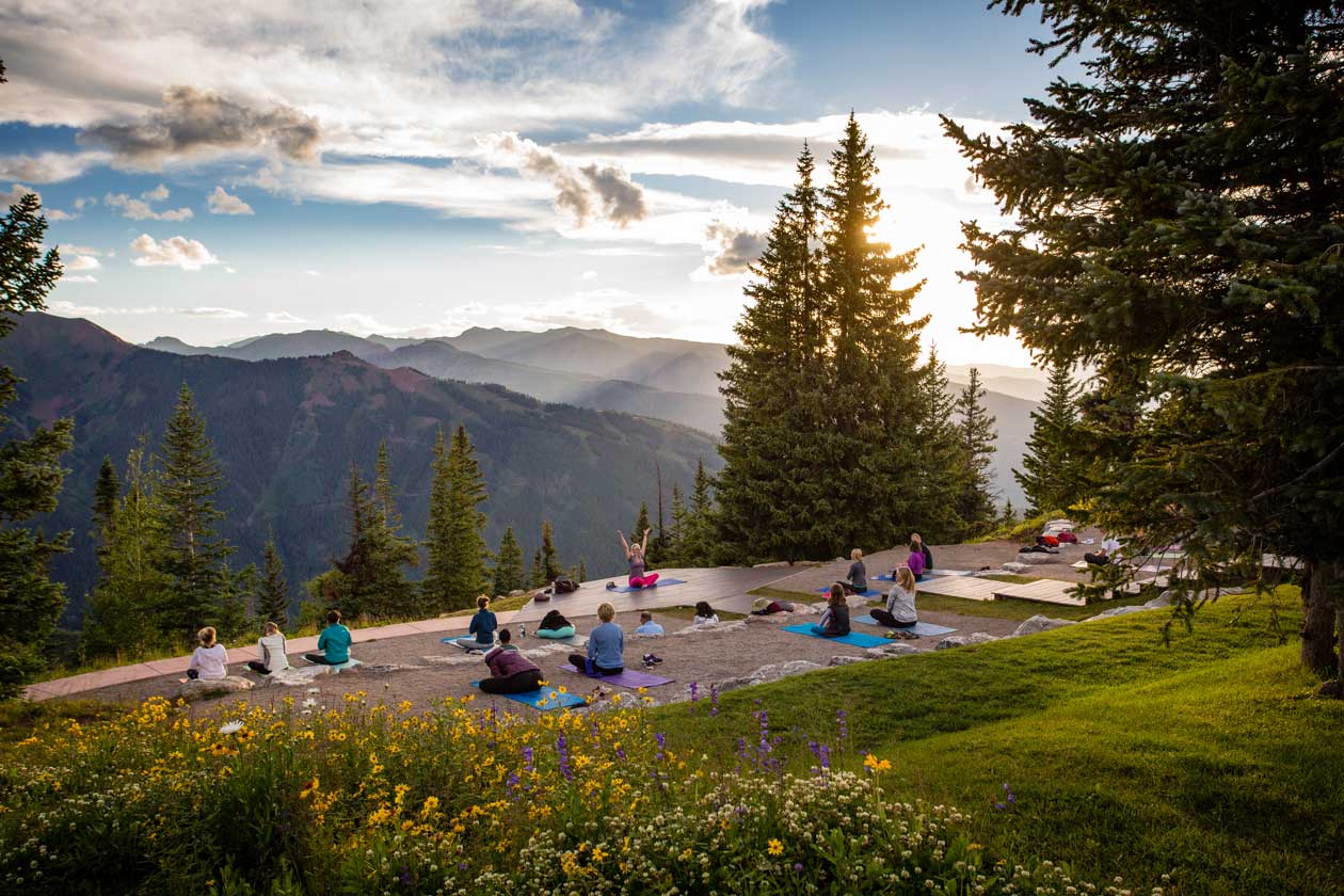 A group of people doing yoga at sunrise on a mountaintop