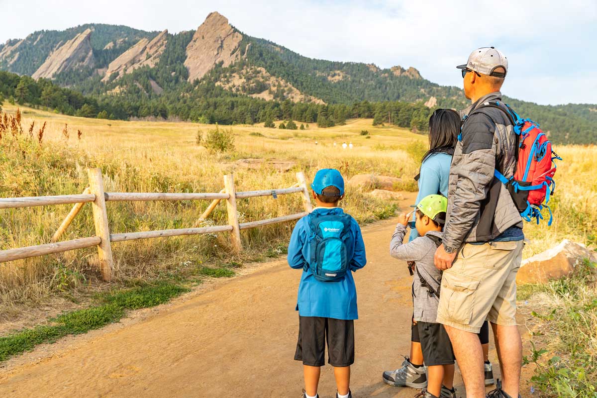 Two adults and two kids take in the view of the Flatirons from the trail