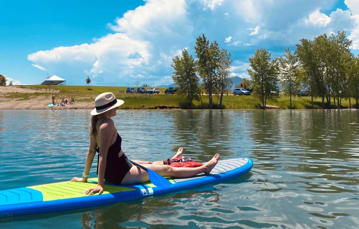 A woman floats on a paddleboard in the middle of a lake