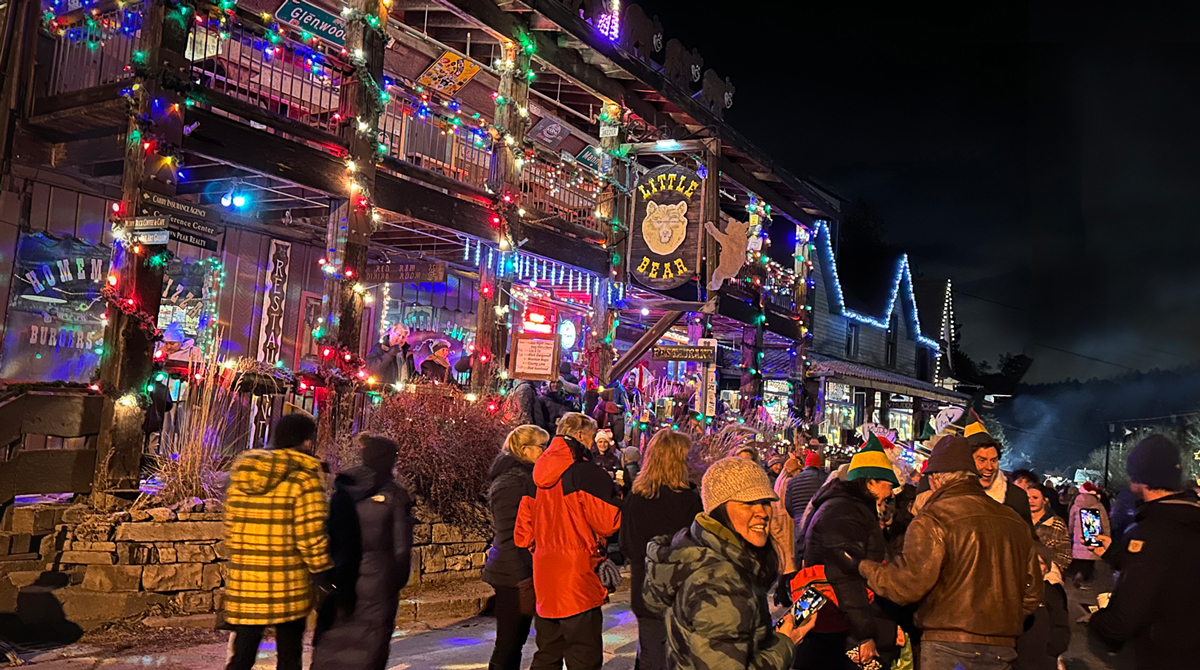 A crowd of people in front of the lit-up buildings of Evergreen for an annual Holiday Walk in downtown.