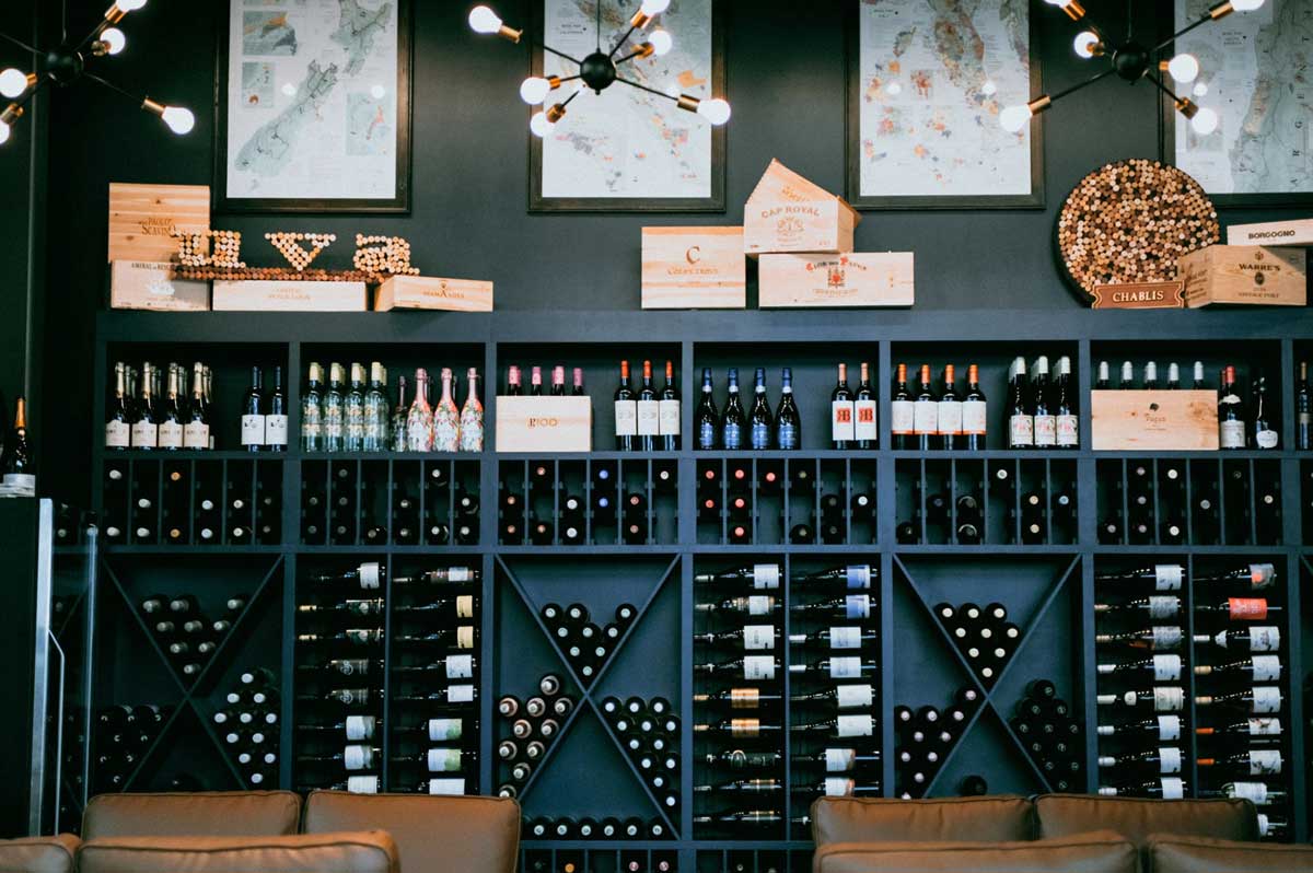 A black wall with shelves and shelves of wine bottles