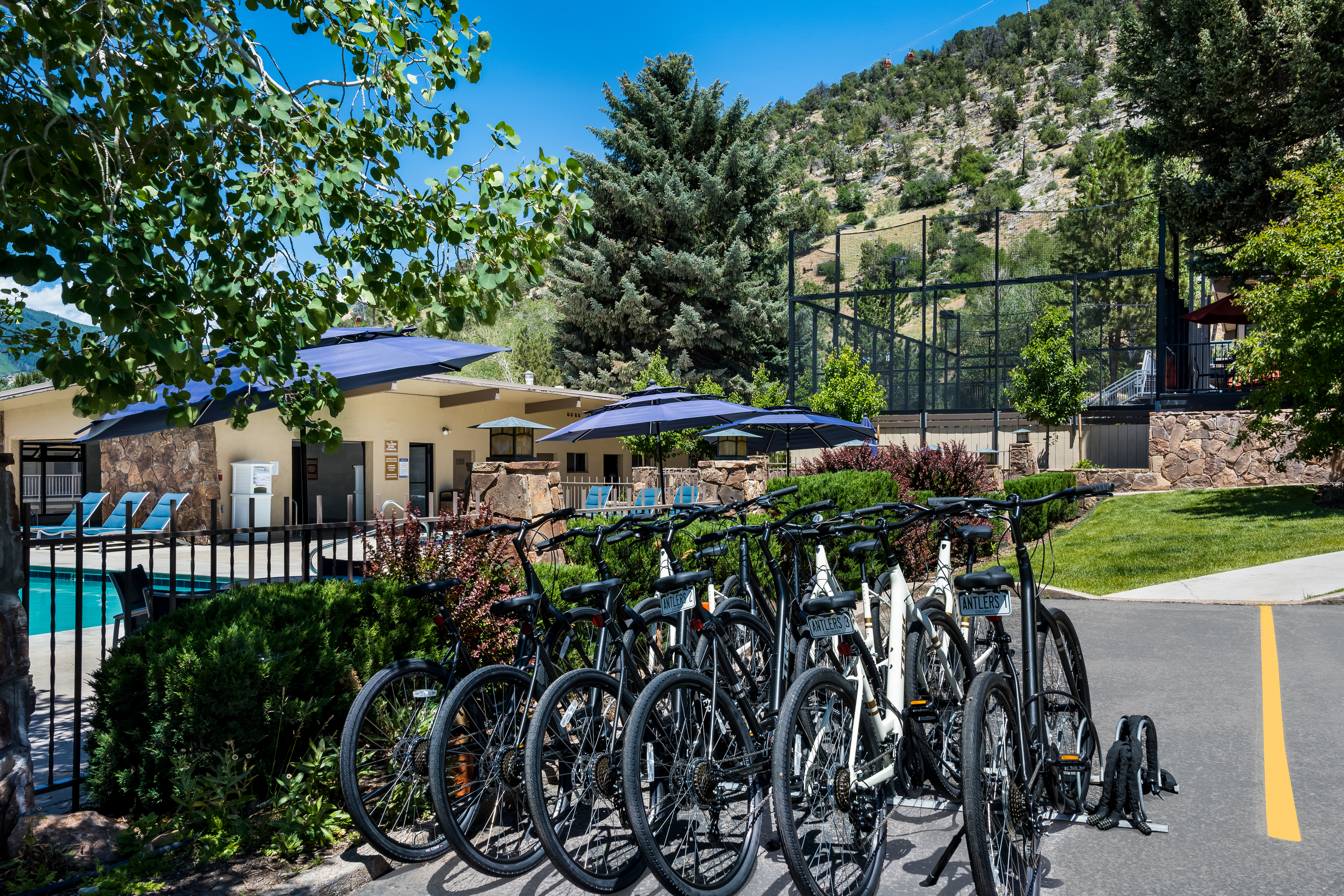Several complimentary cruiser bikes lined up next to a pool with a mountain backdrop at Best Western Antlers in Glenwood Springs, Colorado