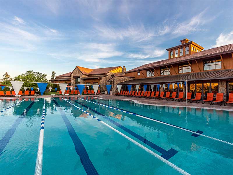 An empty pool with lanes designated for people doing laps in front of a resort building