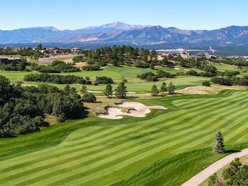 The tidy straight lines of a golf couse fairway with a mountain backdrop