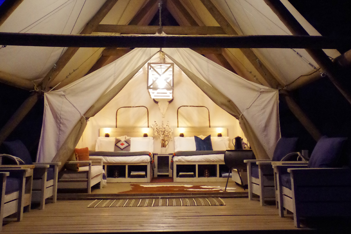 A tent at the glamping resort, Black Tree Resort in Lake George, is brightly lit with solar-powered lights. It is night and the rest of the area is dark.