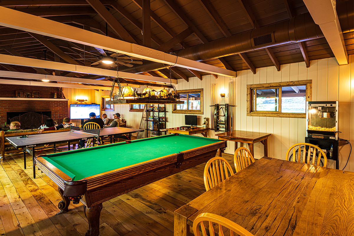 People relax and watch TV in this community space at Harmels on the Taylor. There is also a pool table and dining table.