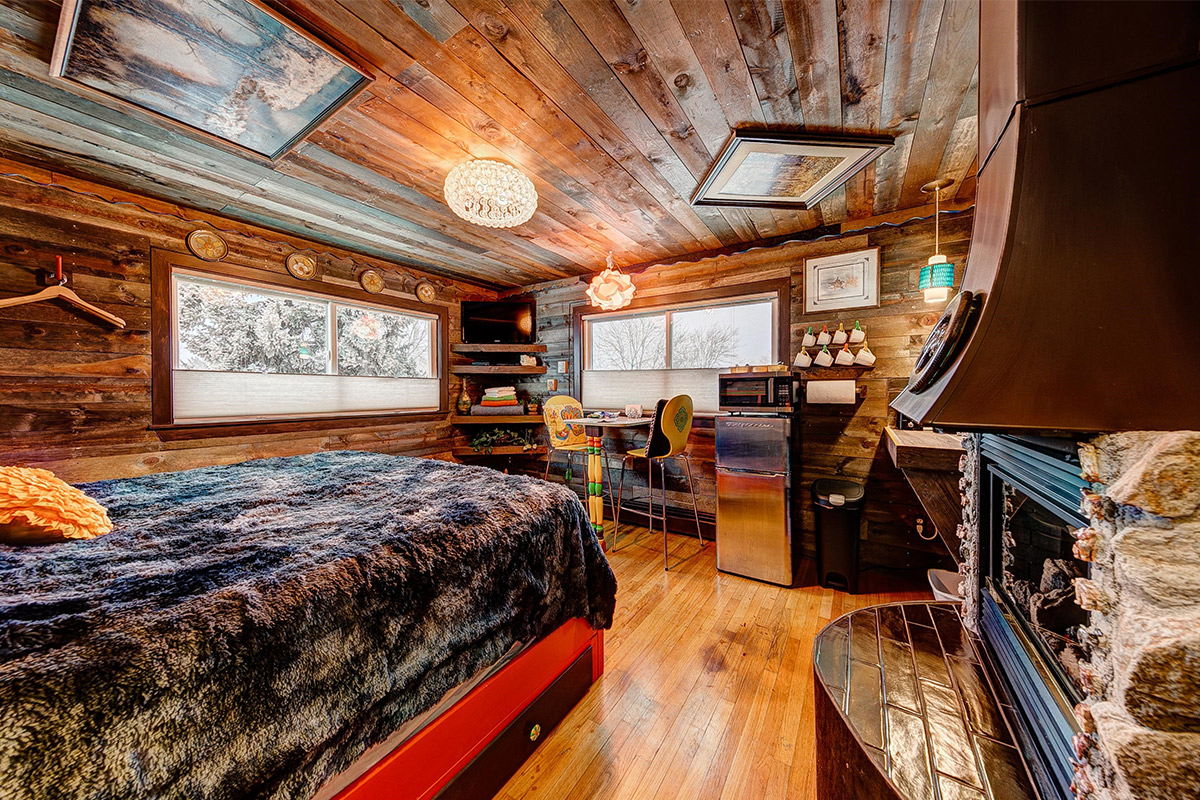 Framed paintings on the ceiling, a thick faux-fur blanket and a stone-line fireplace await guests of the Colorado Room at The Oasis on Eisenhower. 