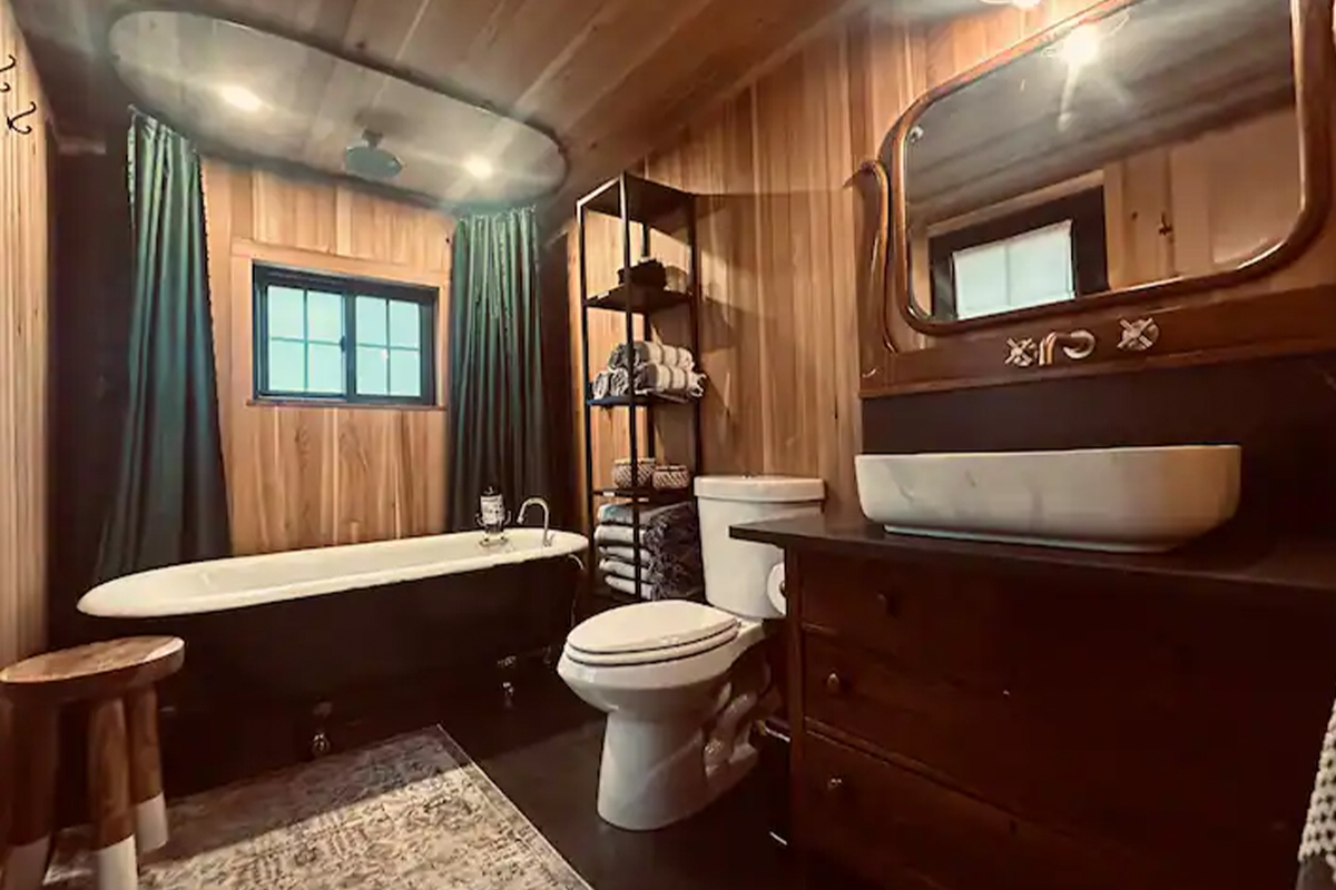 In a cabin near Conifer, Colorado, a wood-paneled bathroom houses a clawfoot tub and rain-style shower.
