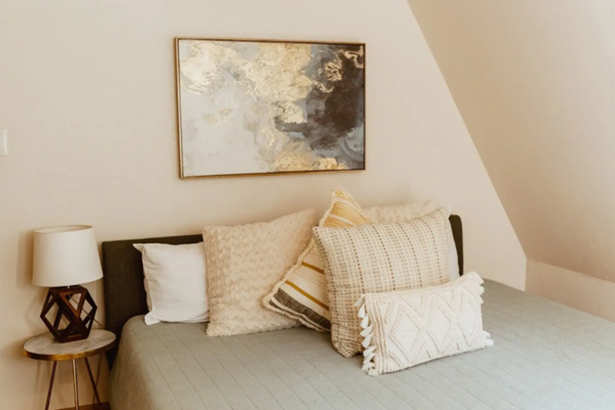 A bed at High Point Hideaway is made and awaits guests. The bed is piled high with thick, soft pillows.