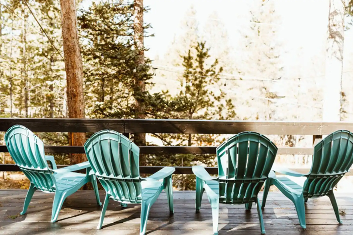 Four turquoise chairs sit on the deck at High Point Hideaway. They offer comfy places to admire the forest and mountain views.