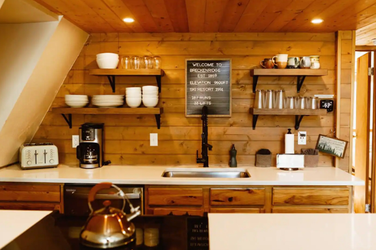 The kitchen at High Point Hideaway features bright, warm-toned wood panels, chic white counters and open shelving.