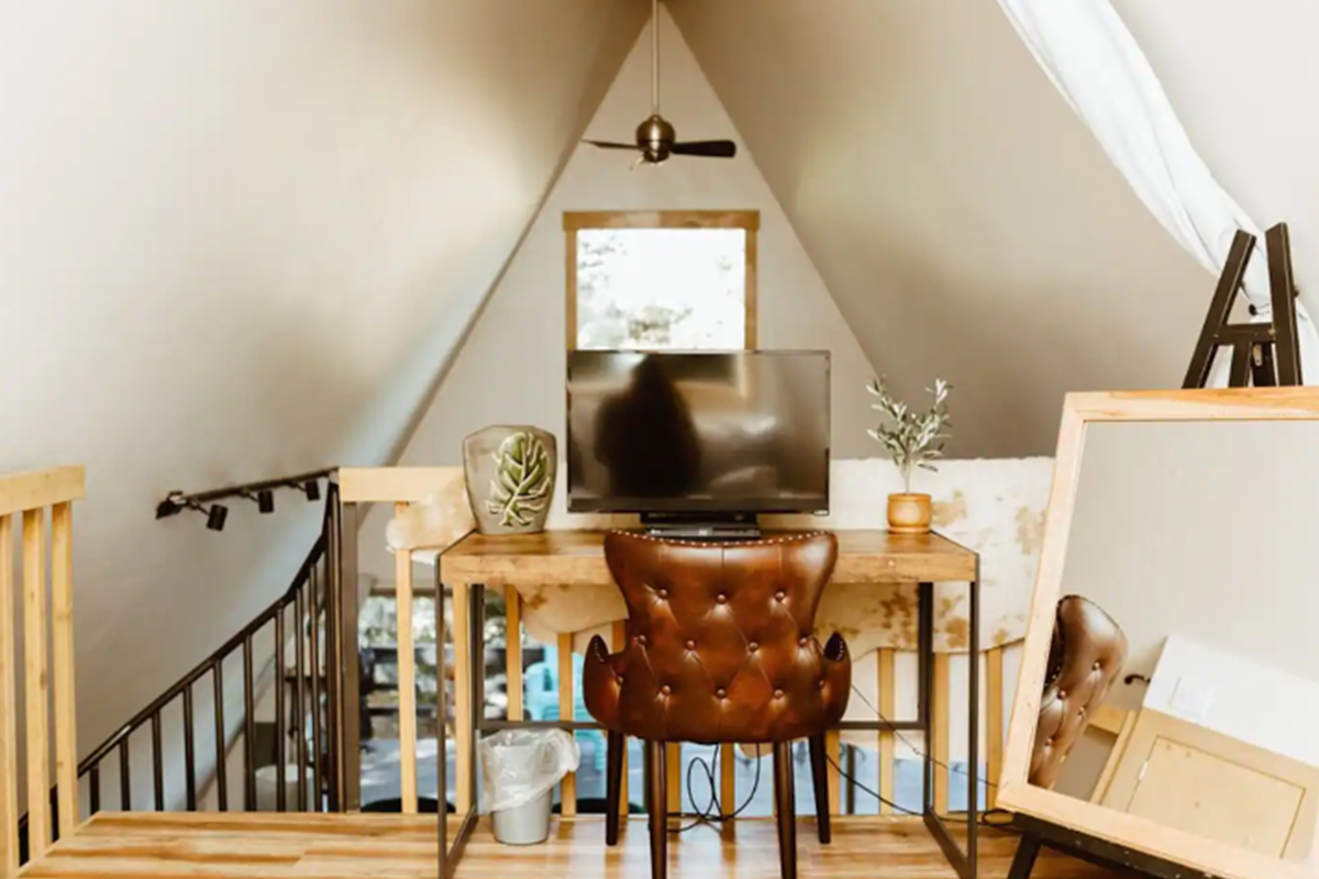 The loft bedroom at High Point Hideaway has a working desk space complete with leather chair and stunning outdoor view.