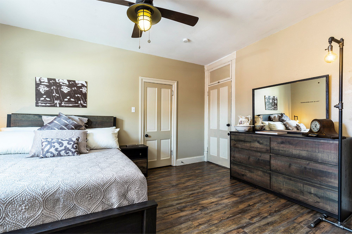 One of the guest rooms at Ore House Inn features dark-wood floors, a bed piled with gray pillows and sheets and miner-style light fixtures.