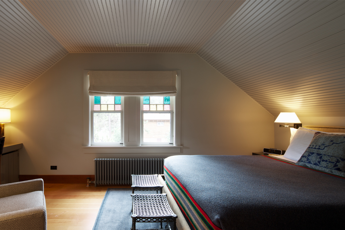 A master bedroom at the Outlook Lodge is ready for new guests. Stained glass windows add a welcoming touch to the room.