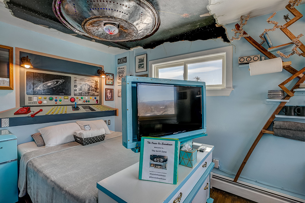A spaceship appears to be crashing through the ceiling above the bed of the Sci-Fi Room at The Oasis on Eisenhower in Loveland, Colorado.