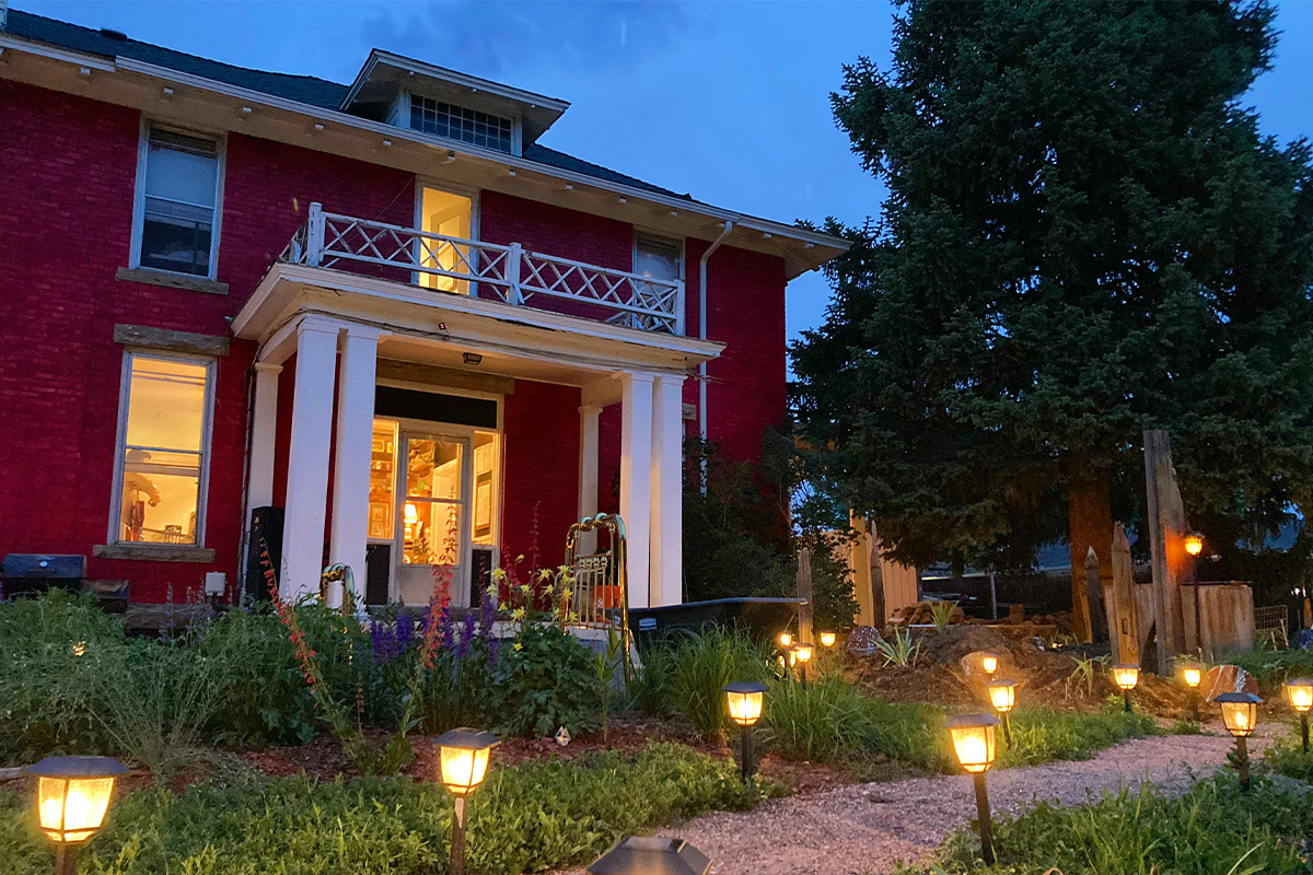Small lanterns along a walking path lead the way to the entrance of the white-trim hotel in Loveland, Colorado, known as The Oasis on Eisenhower.
