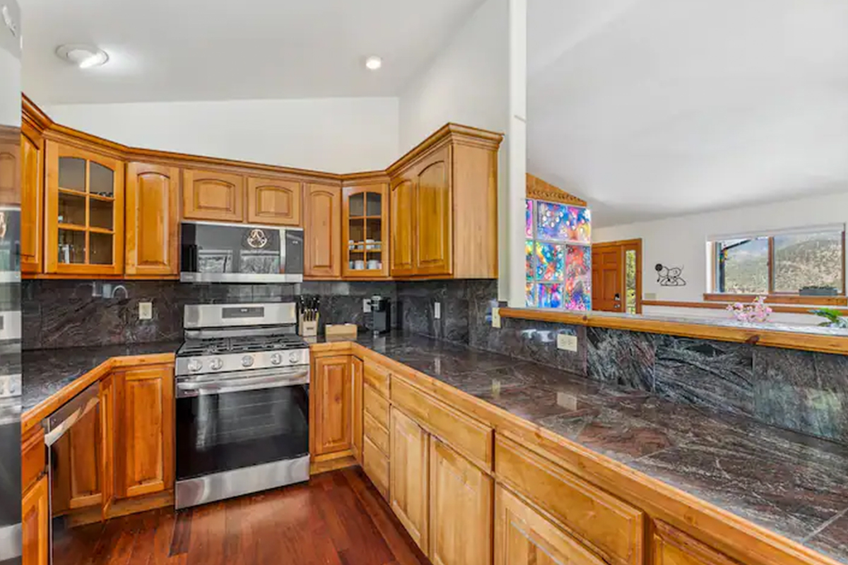 A dark stone countertop pops against the bright wood of the large kitchen at Hummingbird Hill in Colorado.