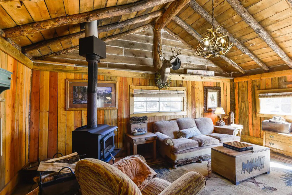 The living room of Idlewild Stagecoach in Lake George, Colorado, has high ceilings with log beams, a wood-burning stove and rustic decor.