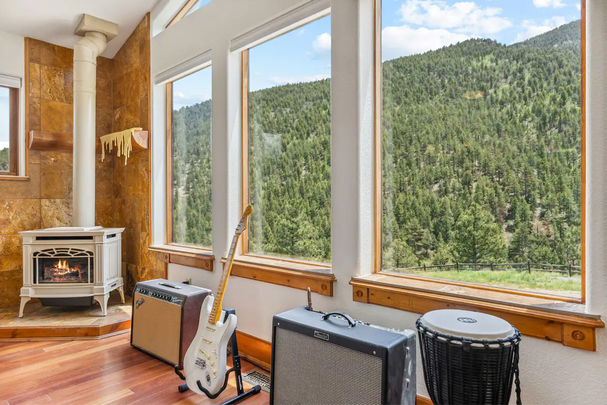 Two amps, an electric guitar and a djembe drum sit in front of massive picture windows in the living room at Hummingbird Hill in Colorado.