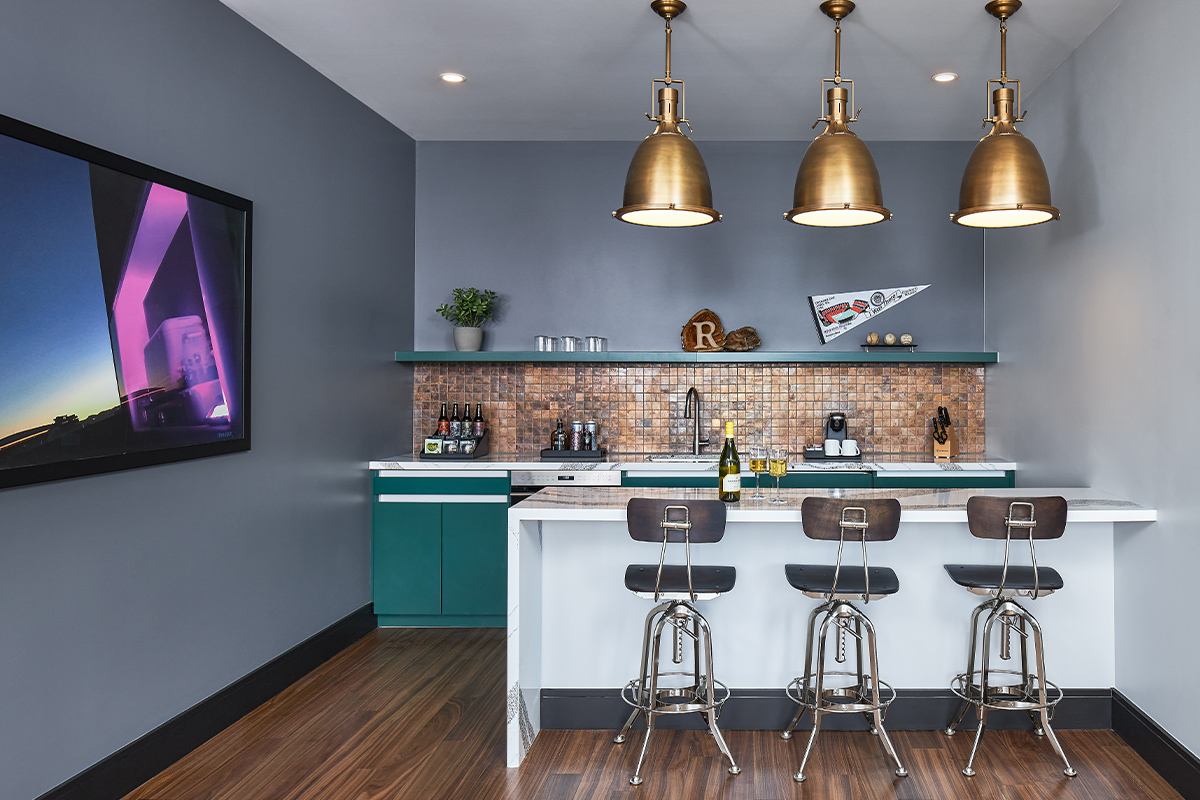 A kitchen at The Rally features a bar, three bar chairs and a sports pennant. 