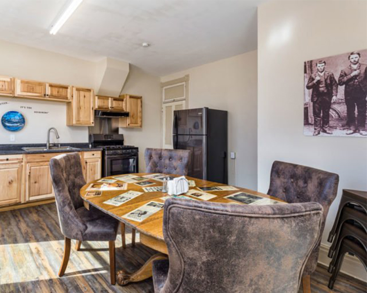 Four suede chairs with bright metallic studs sit around a table decorated with faux documents in the Tombstone-themed suite at Ore House Inn in New Castle. 