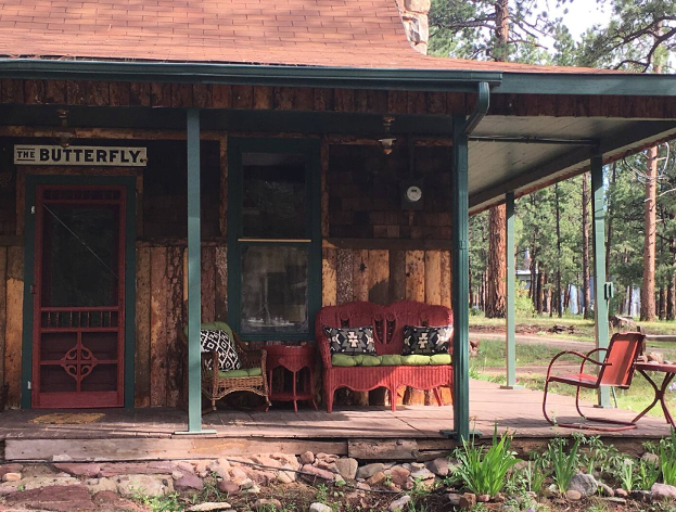 The Butterfly cabin offers a large, shaded deck with green, painted log posts holding it up right off the front of the structure. Here you can sit in chairs and gaze out on the treed Colorado landscape.