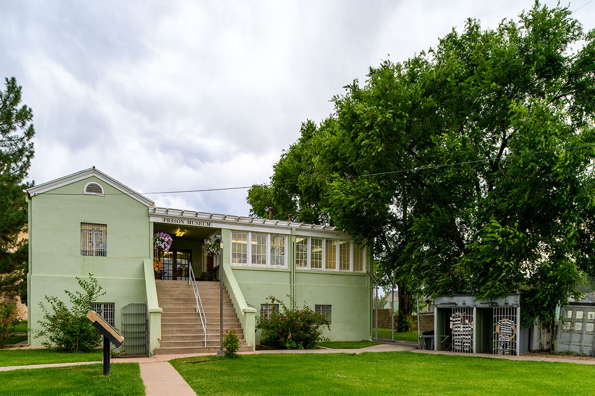 Exterior of a pale green building surrounded by green grass and trees